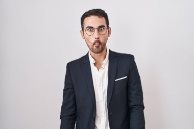 Handsome business hispanic man standing over white background making fish face with lips, crazy and comical gesture. funny expression. 