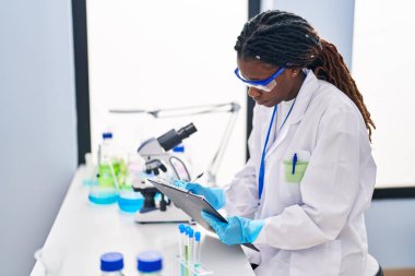 African american woman scientist writing report working at laboratory