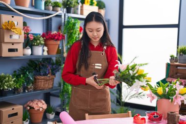 Genç Çinli kadın çiçekçi çiçekçide çiçek buketi yapıyor.