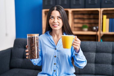 Genç esmer kadın elinde kahve çekirdekleri ve kahve fincanı ile yan tarafa bakıp düşüncelere dalmış.. 