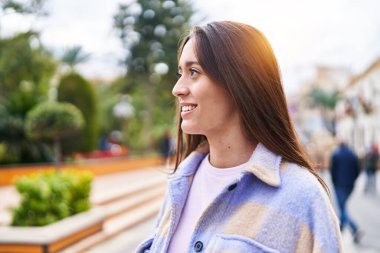 Genç, güzel, İspanyol bir kadın, gülümsüyor. Parkta kendine güveniyor.