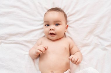 Adorable hispanic toddler smiling confident lying on bed at bedroom