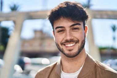 Sokakta kendinden emin gülümseyen İspanyol genç adam.