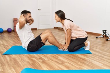 Latin erkek ve kadın çift güler yüzlü spor merkezinde karın kasları egzersizi yapar.