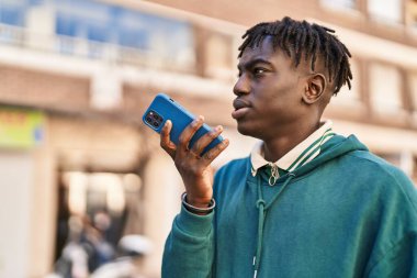 Afro-Amerikalı adam akıllı telefondan konuşuyor. Sokakta ciddi bir ifadeyle.