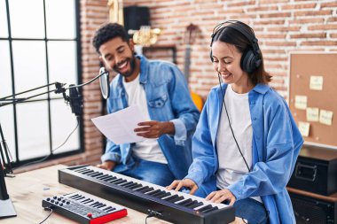 Man and woman musicians singing song playing piano at music studio