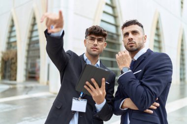Two hispanic men business workers using touchpad working at street