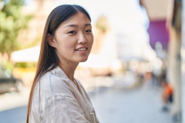 Sokakta kendinden emin gülümseyen Çinli kadın.