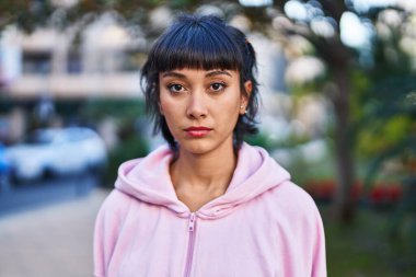 Parkta rahat bir ifadeyle duran genç bir kadın.