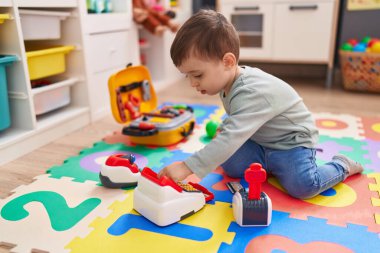 Adorable hispanic boy playing with supermarket game at kindergarten