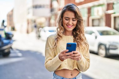 Sokakta akıllı telefon kullanan kendine güvenen genç bir kadın.