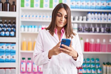 Genç ve güzel bir İspanyol eczacı eczanede çalışan akıllı telefonu kullanıyor.
