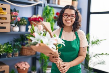 Young woman florist holding bouquet of flowers at florist