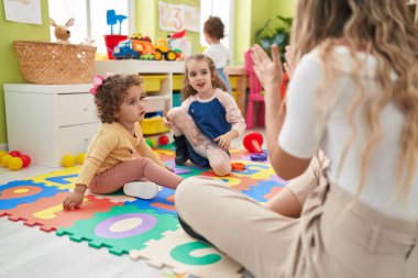 Group of kids having lesson sitting on floor at kindergarten