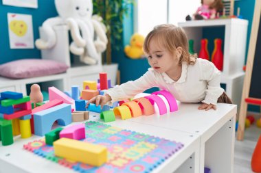 Adorable blonde girl playing with toys standing at kindergarten