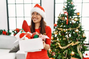 Genç Latin kadın elinde Noel ağacı süsleme kutusu tutuyor.