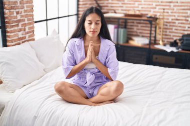 Genç ve güzel İspanyol kadın yoga yapıyor. Yatak odasında oturuyor.