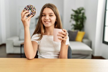 Çok tatlı bir kız kahvaltısını evde, masada yapıyor.