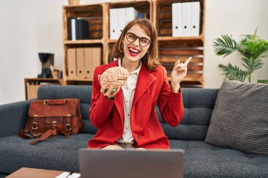 Muayenehanedeki genç esmer kadın elinde beyinle mutlu mesut gülümsüyor. 