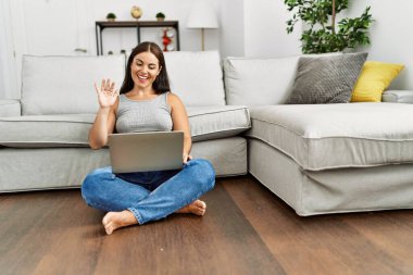 Genç, güzel, İspanyol bir kadın evde oturmuş video görüşmesi yapıyor.