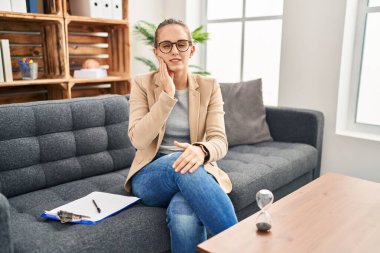 Young woman working at consultation office touching mouth with hand with painful expression because of toothache or dental illness on teeth. dentist 
