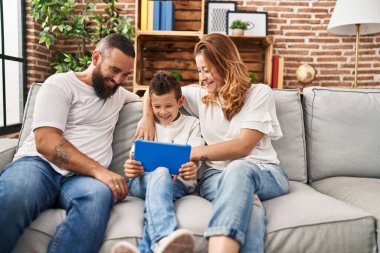Family using touchpad hugging each other sitting on sofa at home