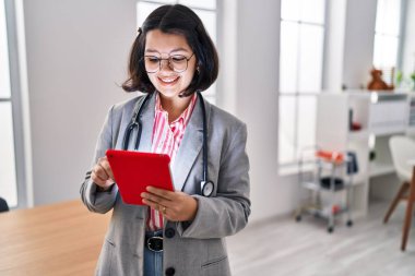 Young woman doctor using touchpad working at clinic