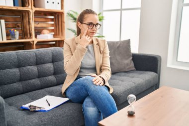 Young woman working at consultation office pointing to the eye watching you gesture, suspicious expression 
