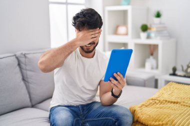 Sakallı İspanyol bir adam kanepeye oturmuş gülümsüyor ve elleri yüzünde şaşkınlıktan gözleri kapatıyordu. kör kavram. 