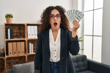 Genç İspanyol kadının elinde dolar var. Korkmuş ve ağzı açık kalmış, şaşırmış ve şaşırmış bir halde. 