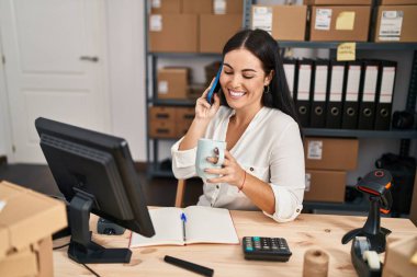 Genç, güzel, İspanyol bir kadın. İş adamı. Akıllı telefondan konuşuyor, ofiste kahve içiyor.