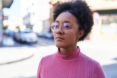 Sokakta ciddi bir ifadeyle yan tarafa bakan Afrikalı Amerikalı kadın.
