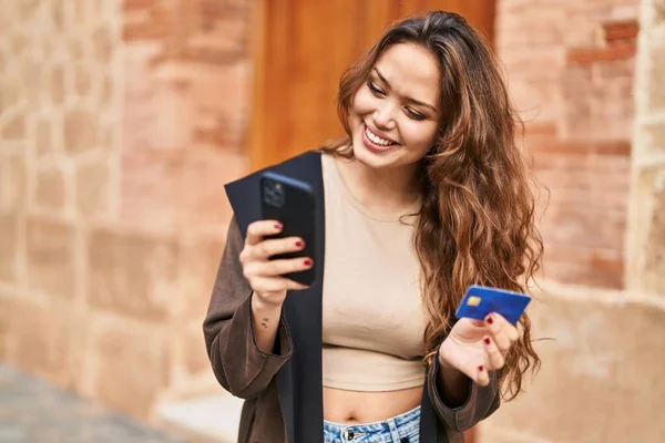 ストリートでスマートフォンやクレジットカードを使用して若い美しいヒスパニック系女性 — ストック写真