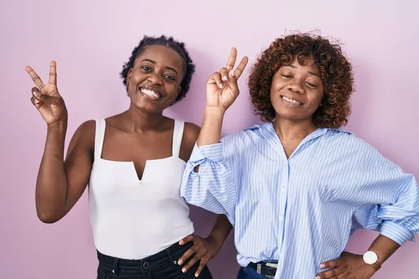 Two African Women Standing Pink Background Smiling Looking Camera Showing — Stok fotoğraf