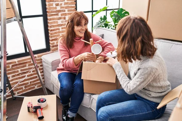 Two women mother and daughter unpacking cardboard box at street