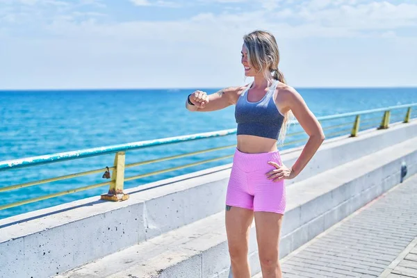 Νεαρή Ξανθιά Γυναίκα Φορώντας Αθλητικά Ρούχα Αναζητούν Χρονόμετρο Στην Παραλία — Φωτογραφία Αρχείου