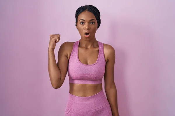 African American Woman Braids Wearing Sportswear Pink Background Surprised Pointing — 图库照片
