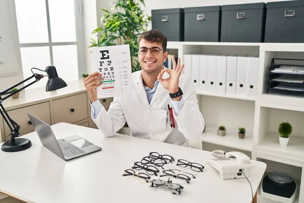 Young Hispanic Man Working Ophthalmology Clinic Doing Sign Fingers Smiling — ストック写真