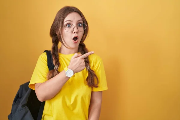 Mujer Joven Caucásica Usando Mochila Estudiante Sobre Fondo Amarillo Sorprendido — Foto de Stock