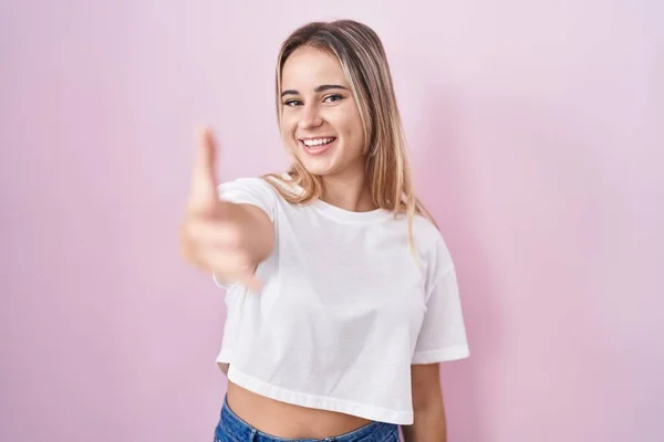 Young Blonde Woman Standing Pink Background Smiling Friendly Offering Handshake — стоковое фото