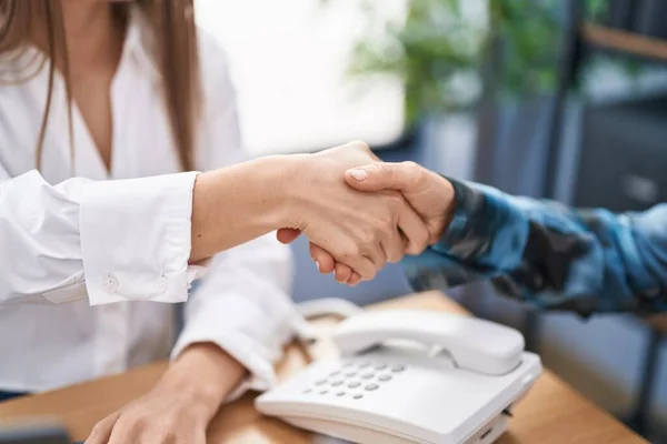 Two women business worker shake hands at office