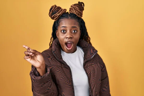 African Woman Braided Hair Standing Yellow Background Surprised Pointing Finger — ストック写真