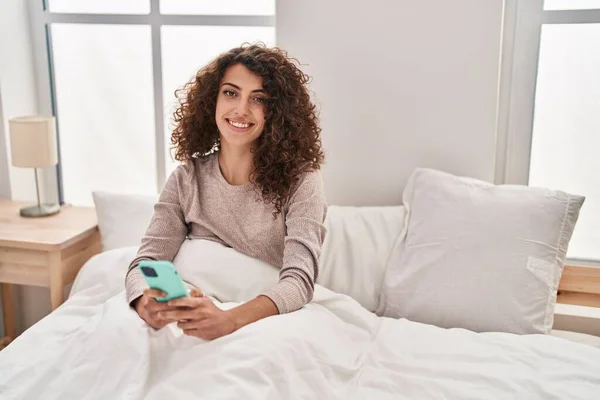 Young Hispanic Woman Using Smartphone Sitting Bed Bedroom — 스톡 사진