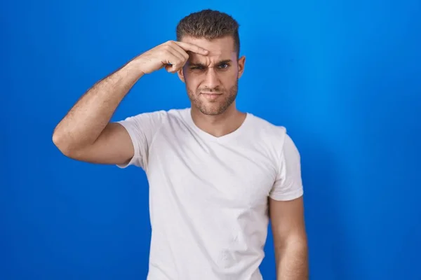 Young Caucasian Man Standing Blue Background Pointing Unhappy Pimple Forehead — Stockfoto