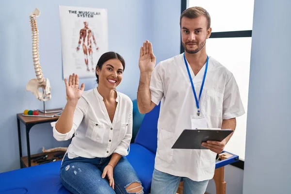 Young Hispanic Woman Physiotherapist Appointment Waiving Saying Hello Happy Smiling — Stok fotoğraf