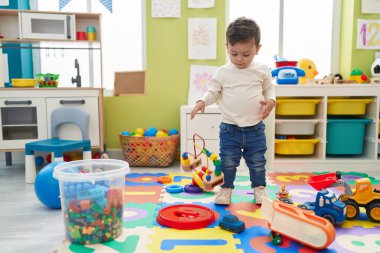 Adorable hispanic boy standing at kindergarten
