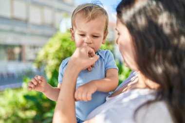 Anne ve oğlu parkta rahat bir ifadeyle duruyorlar.