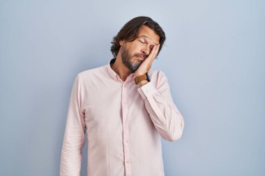 Handsome middle age man wearing elegant shirt background thinking looking tired and bored with depression problems with crossed arms. 