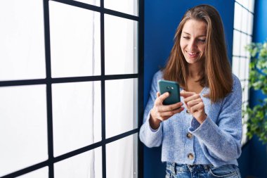 Young woman using smartphone standing at home