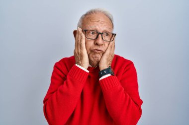 Gri saçlı yaşlı adam arka planda duruyor. Yorgun eller yüzünü, depresyonunu ve üzüntüsünü kapatıyor. Sorunları yüzünden üzgün ve sinirli. 